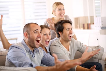 Cheerful group of friends watching football game on tv