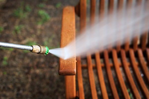 A hose spraying water on a piece of outdoor furniture